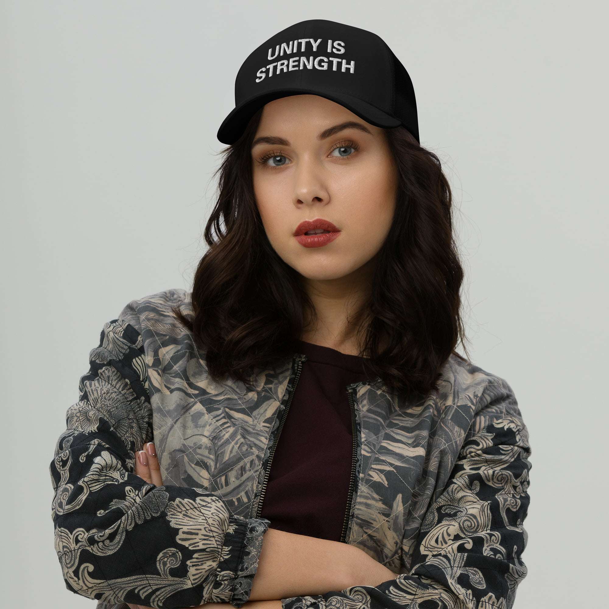 Rastafarian Caps front female model view with Unity is Strength embroidered across the front. Black cap in the trucker style. Great for island vacation or Reggae Festival.